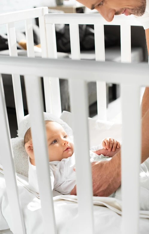 Dad reached into crib to pick up baby.
