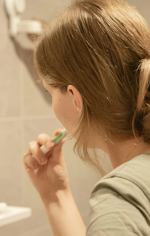 View from behind of girl brushing her teeth.