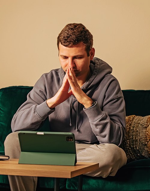 Teen on sofa looking at laptop during virtual intensive outpatient program.