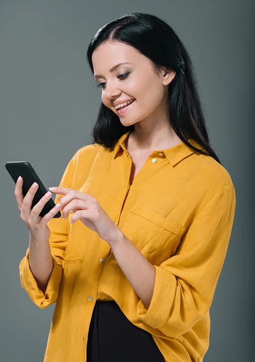A woman smiles as she surfs the web on her smartphone.