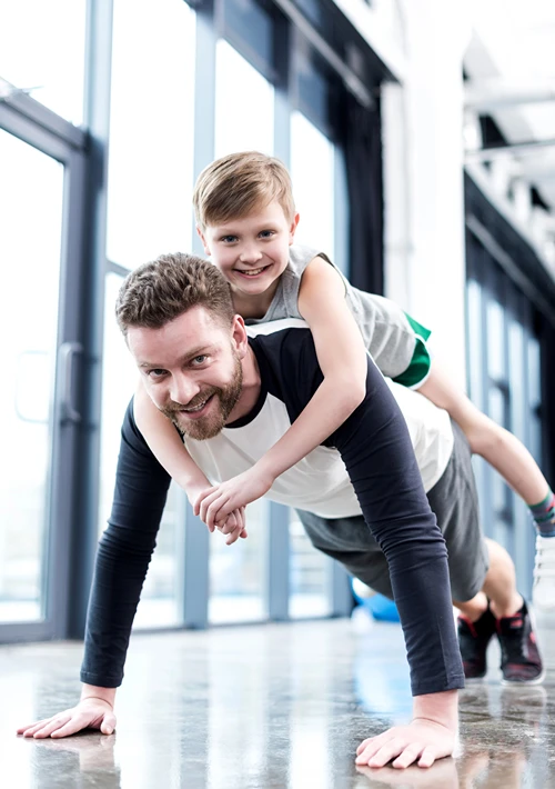Dad doing pushups with son in his back.