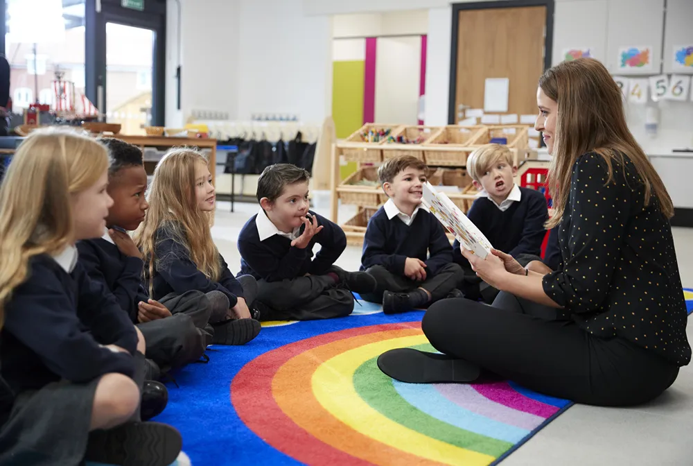 Young students seated on rug on floor for story from their teacher.