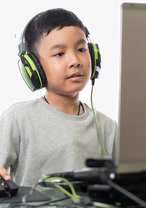 A middle school aged boy wearing headphones as he interacts online.