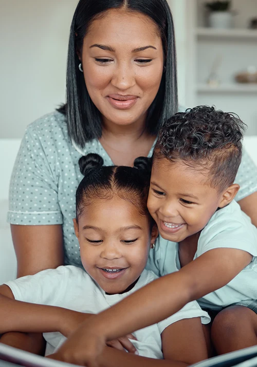 Mother reading a story book to her son and daughter.