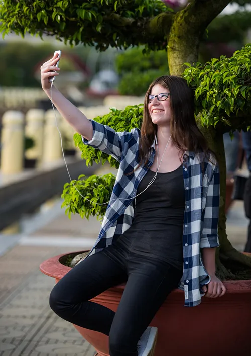A teen girl in a parking taking a snapchat selfie.