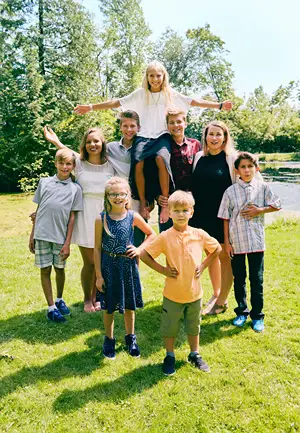 A large blended family poses in the park for a photo.