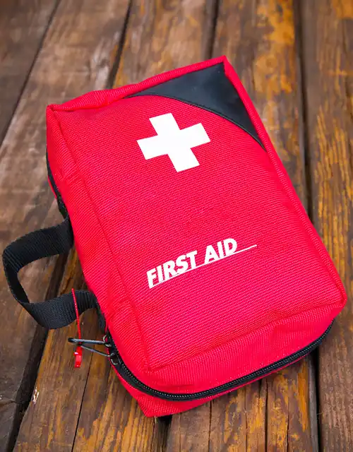 A first aid bag lays on a wood stained deck.