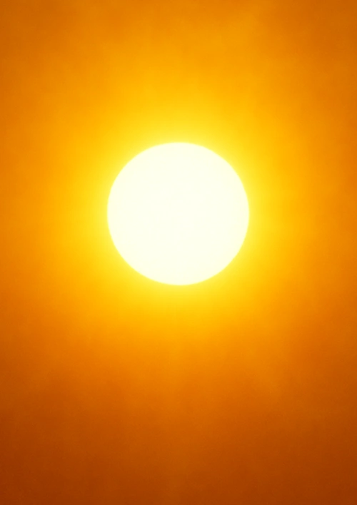 The bright sun shines in an orange sky.