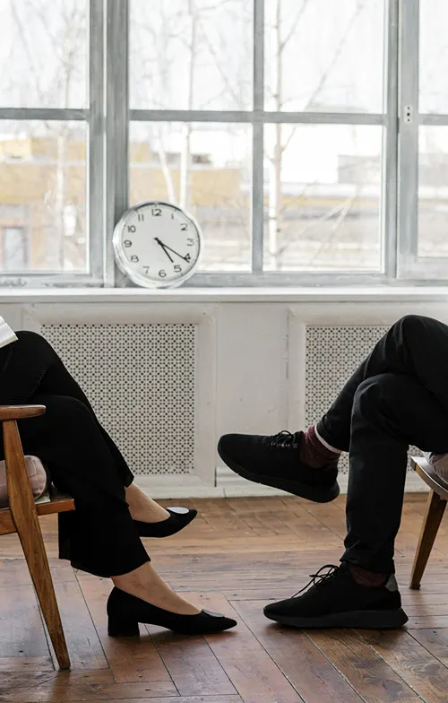 Legs crossed of a man and a woman seated across from each other.