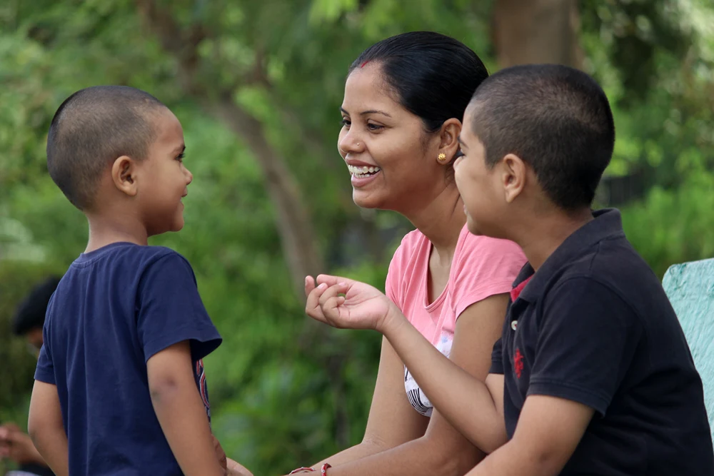 Mother and two boys are laughing smiling as they talk.