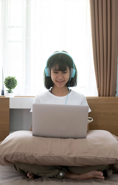 A female student wearing headphone with online tutor.