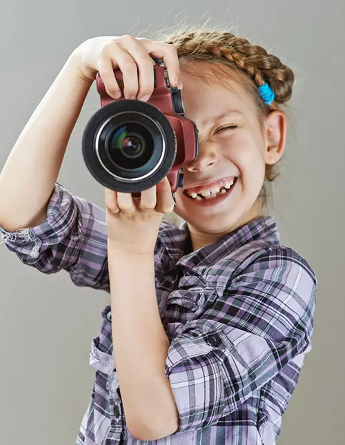A tween girl smiles and points her digital camera for the perfect shot.