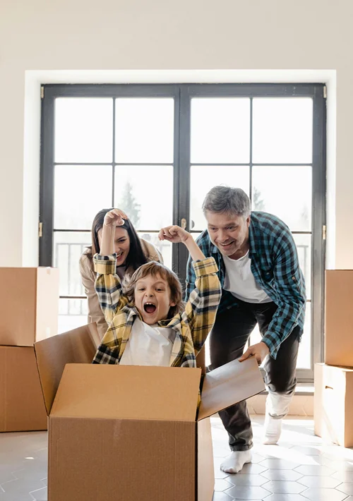 Parents pushing their child in a cardboard box.