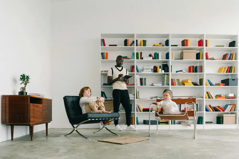 A psychologist stands between two young kids sitting in chairs.