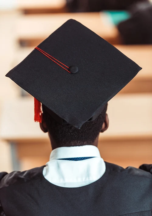 View from behind of a high school graduate in his robe and grad hat.