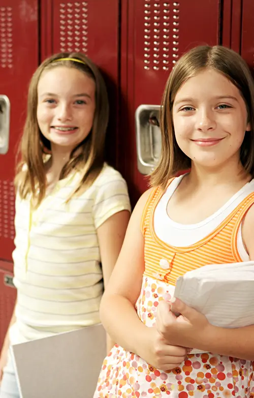 Two middle school girls in front of their school lockers.