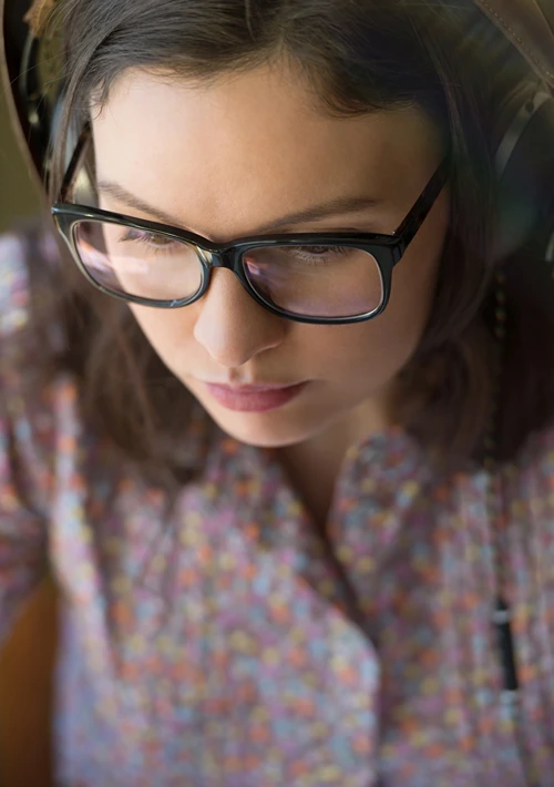 Female student with glasses studying with headphone on.