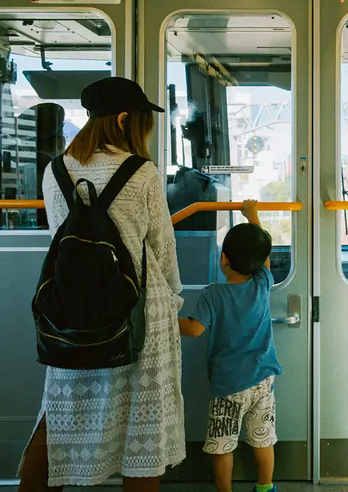 Mother and Son holding rail as they stand in a city train.