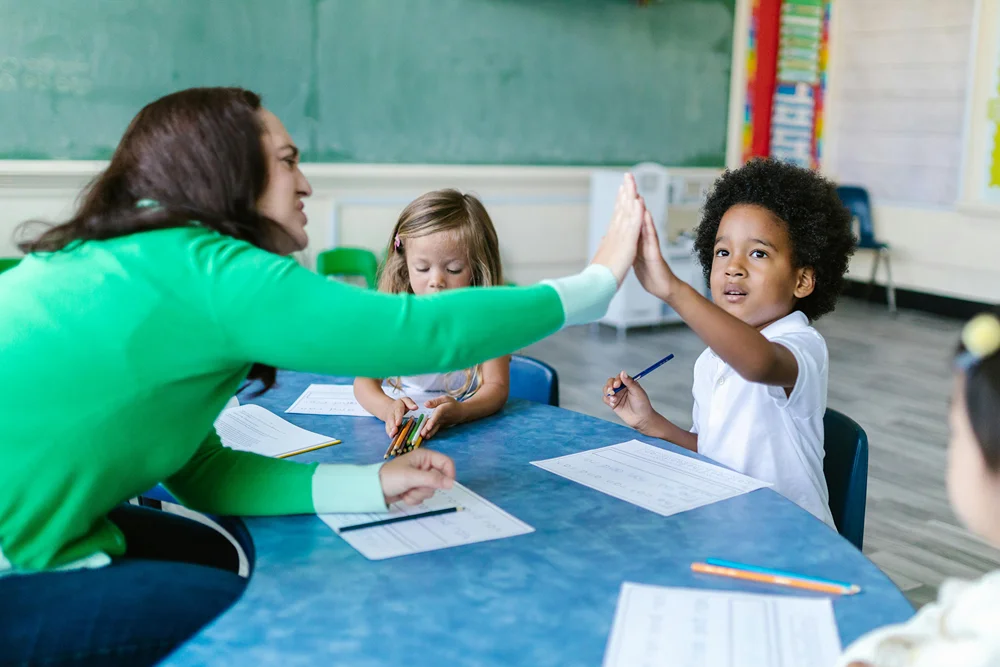 Teacher in work room with kindergarten aged children.