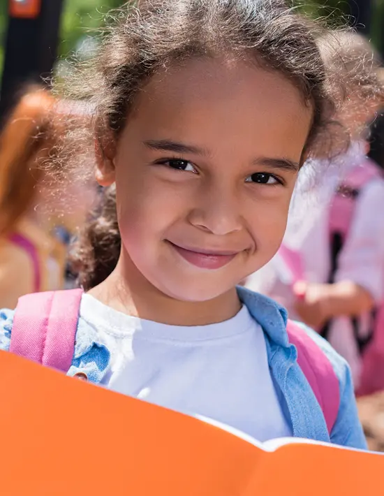A middle school aged girl smiles while looking over her open notebook.