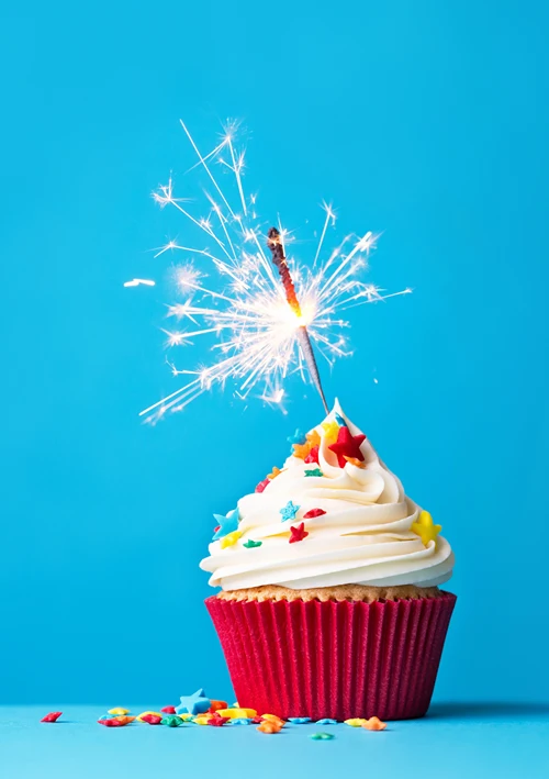 A sparkler burns on a cupcake.