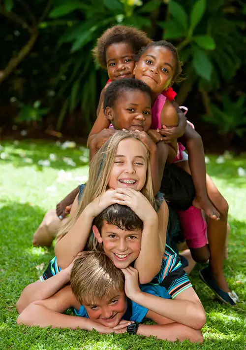 Smiling kids stacked on top of one another posing for a picture.