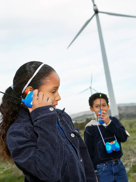 A boy and girl talking and listening to someone on their walkie talkies.