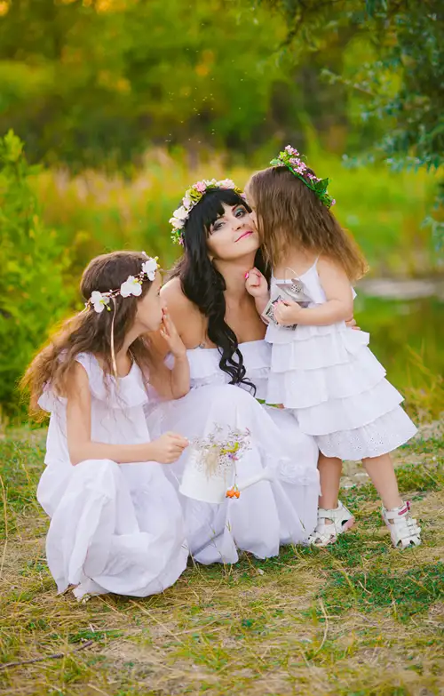 A photo shoot outdoors of a mom in a wedding dress with her kids.