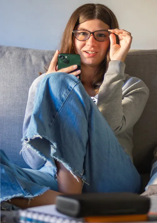 A teen girl on living room sofa looks up as her picture is taken