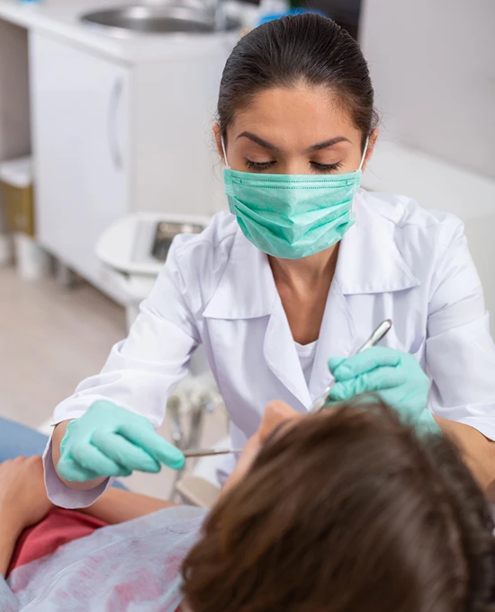 View from behind child's head as female dentist inspects their mouth.