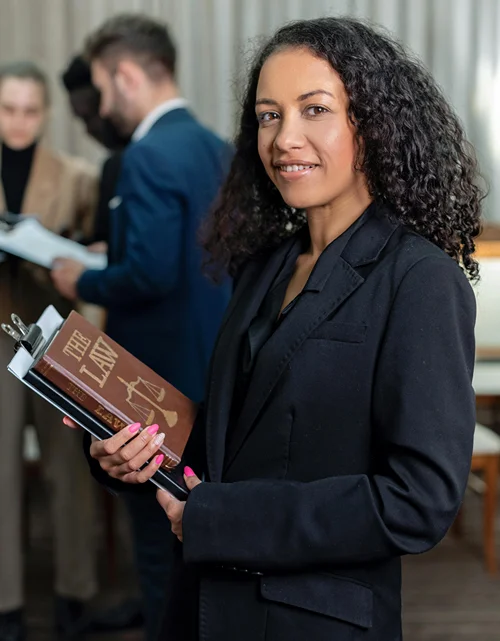 A female law student smiles as she holds a text book entitled The Law.