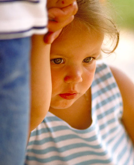 Close up of cute little girl holding on to mom’s hand.