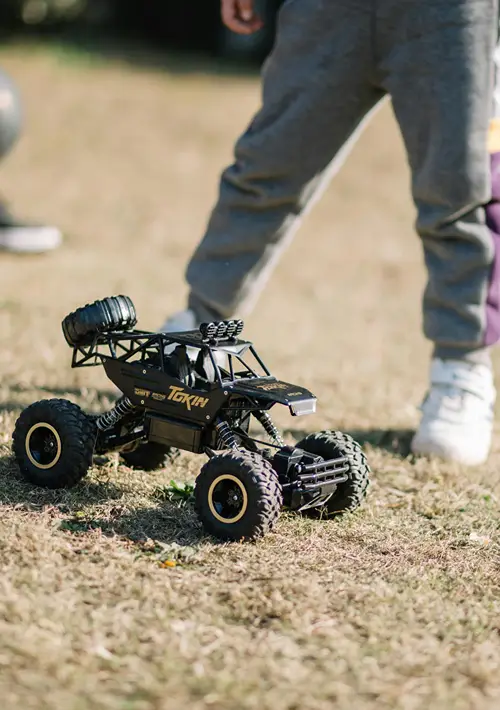 A boy stands over his remote control car.