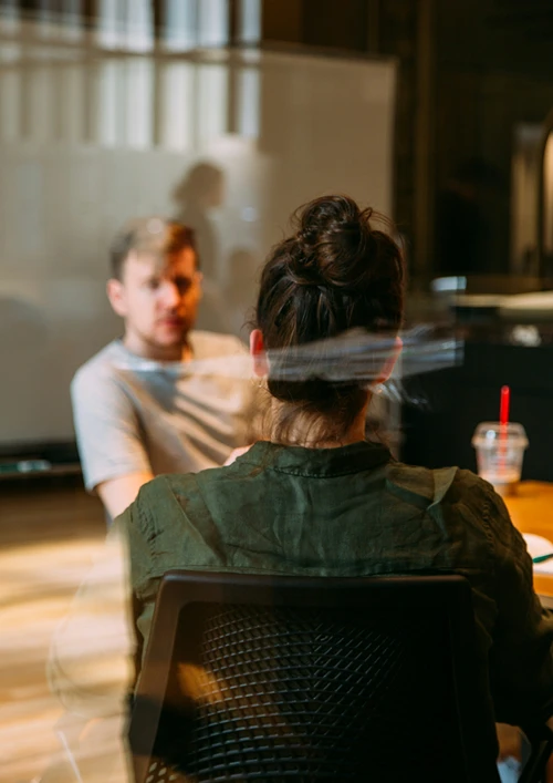 View of a female having a meeting with a casual dress out of focus man.
