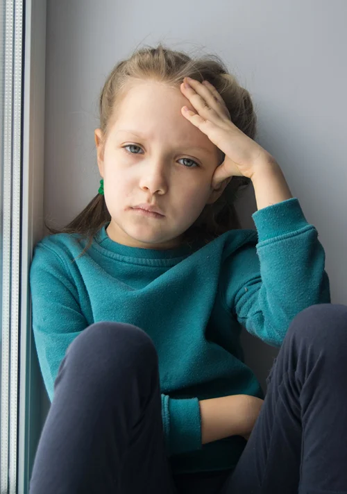 A girl sitting in a corner showing signs of anxiety.