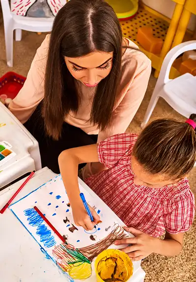 A child is coloring while mom watches.