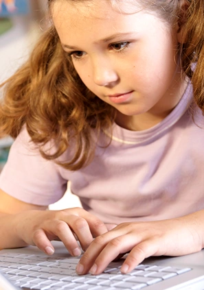 Close up of a girl with fingers on a computer keyboard.