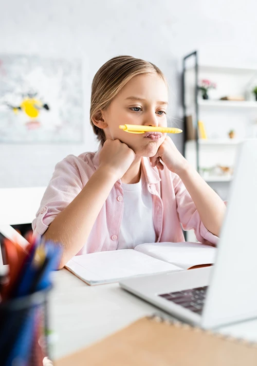 A middle school aged girl with notebook listens to online class on her laptop