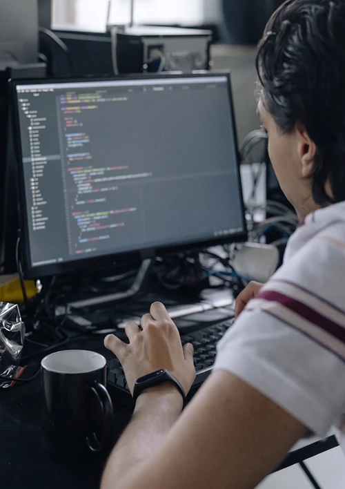 A man is writing code on his computer at work.