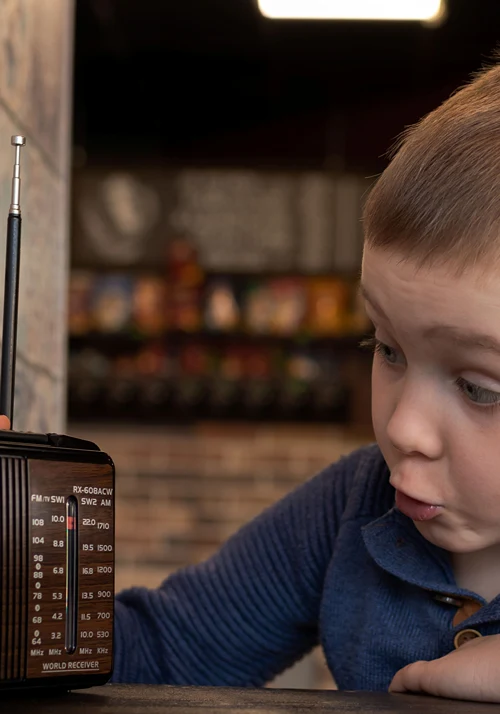 Excited young boy looking curiously at a vintage world receiver radio.