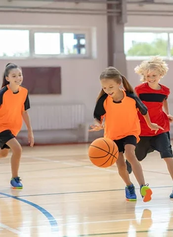 Boys and girls playing basketball at kids camp.