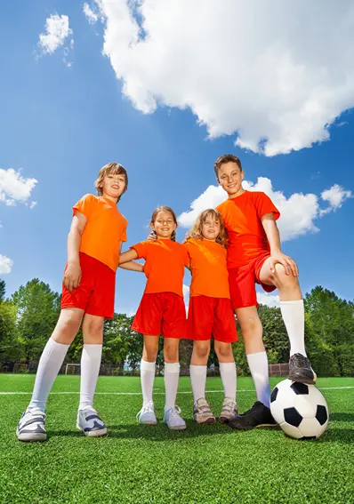 Two boys and two girls on a soccer field with a soccer ball.