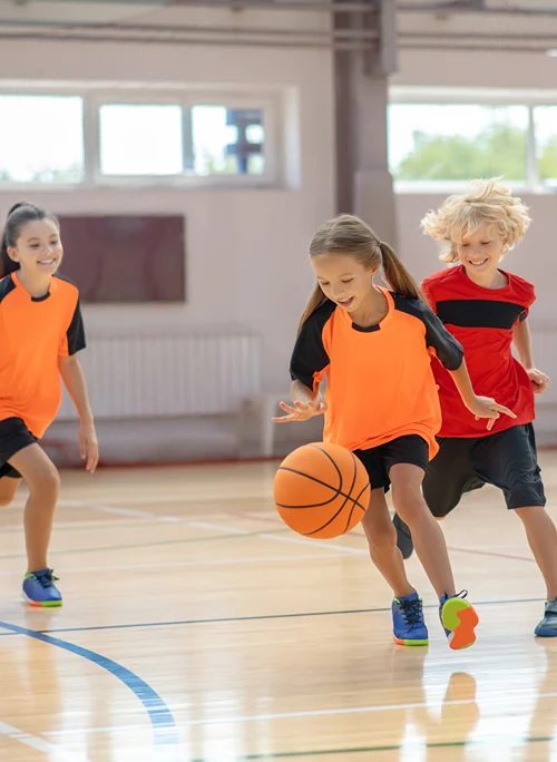 Boys and girls playing basketball at kids camp.