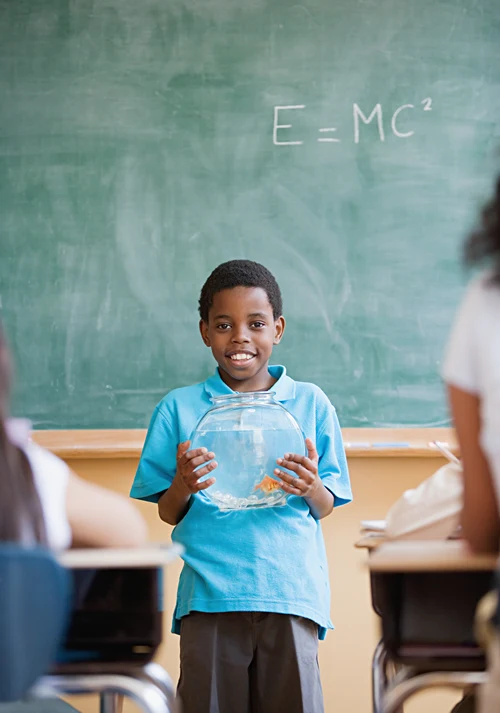 Boy giving a presentation in classroom while holding a fish bowl