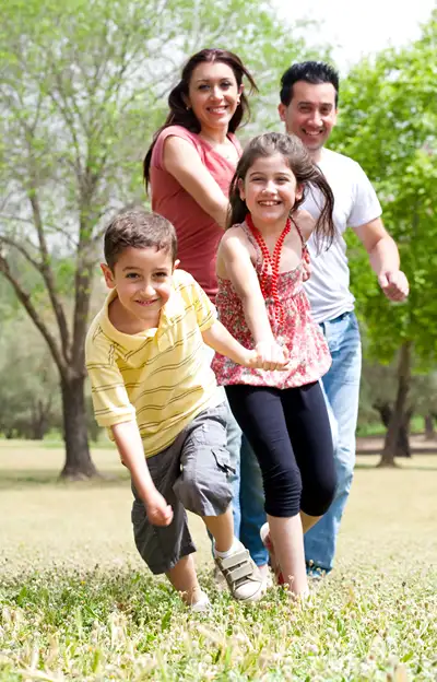 Happy family holding hands and running in a park.