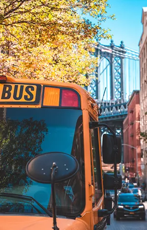 A School buss in Brooklyn with Manhattan bridge in the background.