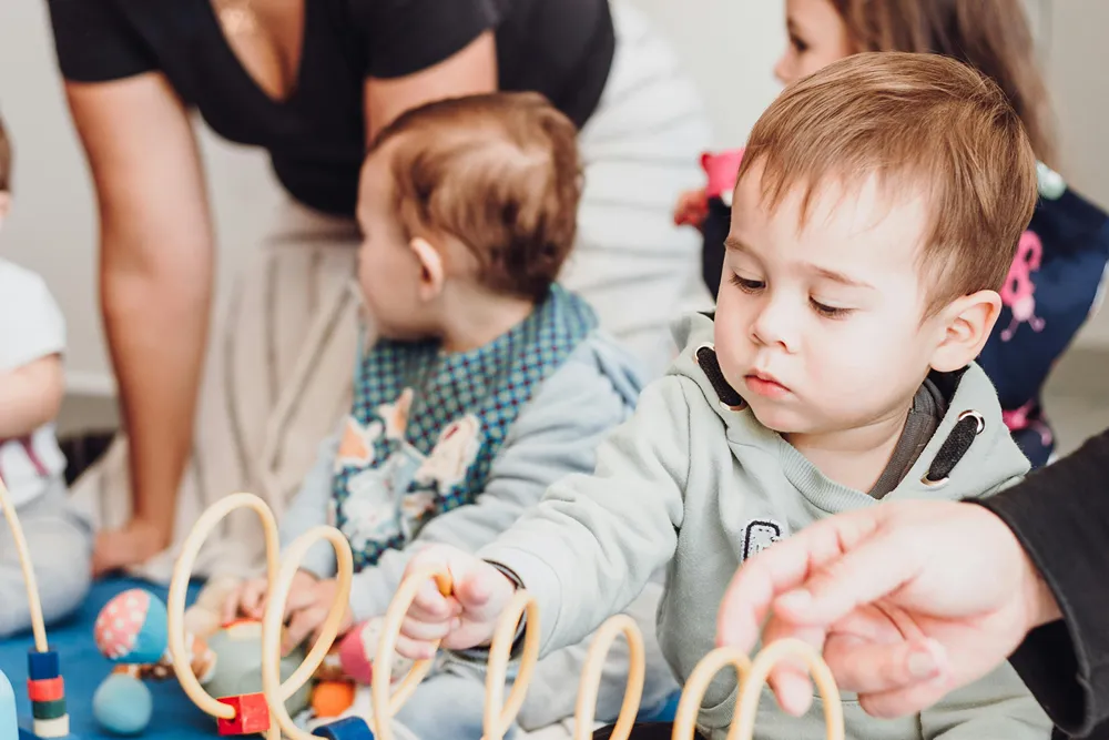 Toddlers playing with toys with caregivers.