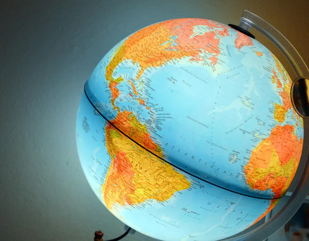 An illuminated desktop world globe showing the Atlantic Ocean, North and South America, and Western Africa.