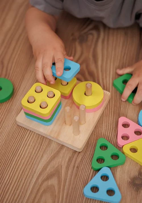 The hands of a small child playing on the follow with small learning toy.