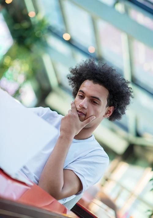 A male African American student intently focused on a project on his computer.